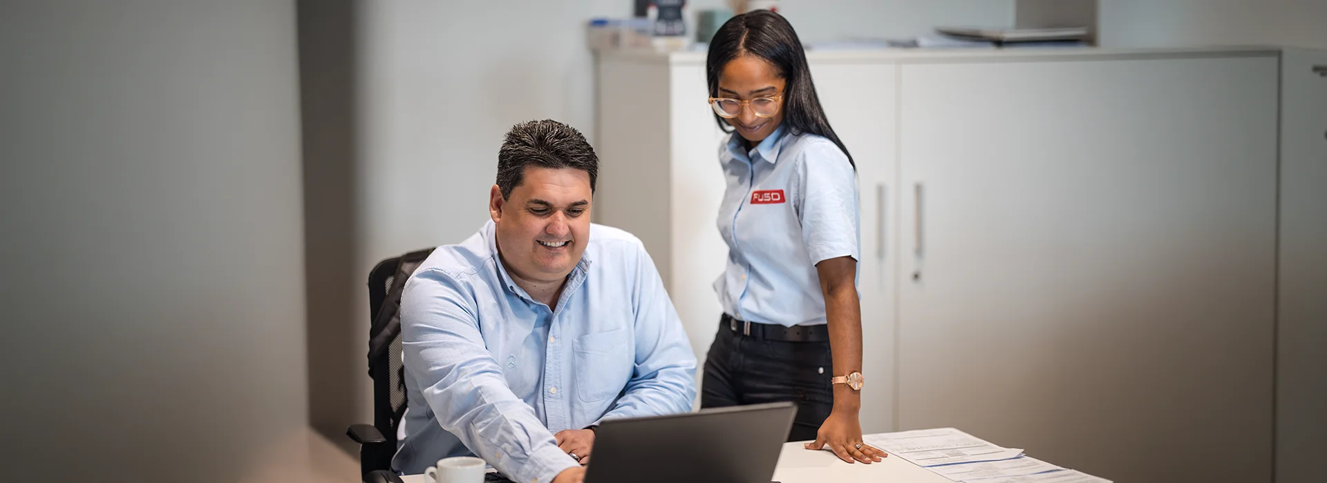 Two colleagues reviewing fleet data on a laptop at an office desk