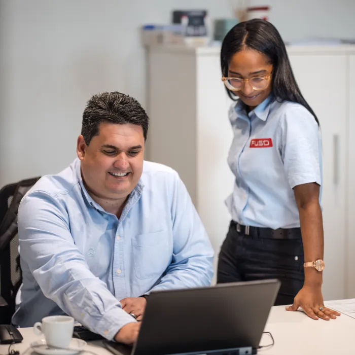 Two colleagues reviewing fleet data on a laptop at an office desk